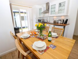 A kitchen with wooden dining table set with plates bowls wine glasses and a flower vase at Cape 14 in Yarmouth
