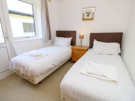 A bedroom with two single beds with white linens a wooden nightstand and a lamp between at Cape 14 in Yarmouth