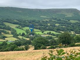 A rural landscape with green fields trees and hills at White Haywood Farmhouse & Barn in Craswall