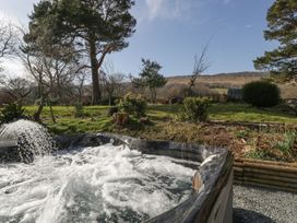 An outdoor hot tub with water jets in a garden with trees and hills in the background at White Haywood Farmhouse & Barn in Craswall