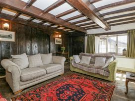 A living room with two sofas a red patterned rug and wooden ceiling beams at White Haywood Farmhouse amp Barn in Craswall