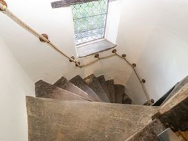 A narrow stone spiral staircase with a rope handrail and a window with leaded glass at White Haywood Farmhouse & Barn in Craswall
