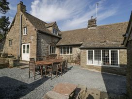 An outdoor patio area with a wooden table and chairs next to a stone farmhouse at White Haywood Farmhouse & Barn in Craswall