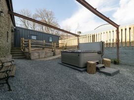 An outdoor area with a hot tub logging stools a bench gravel ground and wooden fencing at White Haywood Farmhouse & Barn in Craswall