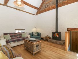 A living room with a wood stove a wooden chest coffee table two sofas and exposed wooden beams at White Haywood Farmhouse & Barn in Craswall