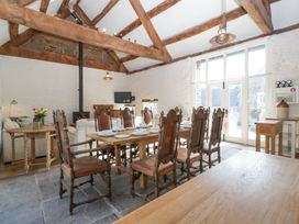 A dining area with wooden table and chairs near a sitting area with white sofas and a fireplace at White Haywood Farmhouse & Barn in Craswall