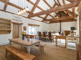 A dining room with wooden tables benches and chairs and exposed wooden beams at White Haywood Farmhouse & Barn in Craswall