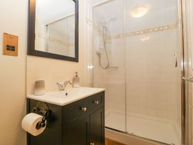 A bathroom with a sink and mirror next to a glass shower enclosure at White Haywood Farmhouse & Barn in Craswall