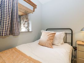 A bedroom with a bed with beige and white bedding next to a window with checkered curtains at White Haywood Farmhouse & Barn in Craswall