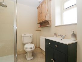 A bathroom with a white toilet a black vanity with sink and faucet a wooden wall cabinet and a glass shower door at White Haywood Farmhouse & Barn Craswall