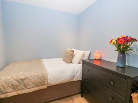 A bedroom with a single bed and a dark dresser with a vase of flowers and a lamp at White Haywood Farmhouse & Barn in Craswall