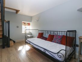A room with a metal framed daybed with cushions near a window and wooden stairs at White Haywood Farmhouse & Barn Craswall