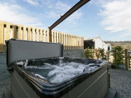 An outdoor hot tub with bubbling water near a wooden fence and a barn at White Haywood Farmhouse & Barn in Craswall