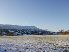 A snow-covered field with scattered trees and hills in the background at White Haywood Farmhouse & Barn in Craswall