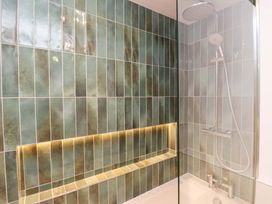 A shower with tiled walls and a glass partition at 5 Lombard Street Porthmadog