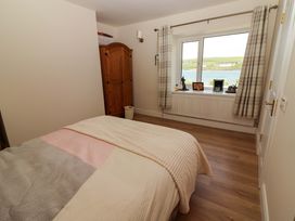 A bedroom with a bed and a window overlooking a body of water at O'Connell's Lodge, Portmagee, County Kerry