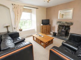 A living room with a sofa, coffee table, and television at Sygun Cottage in Nant Gwynant