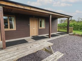 A wooden cabin porch with a door and windows and a picnic table outside at Sycamore in Cowbridge