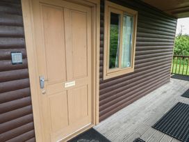 An exterior door with a keypad on the wall and a window on a wooden cabin at Sycamore in Cowbridge