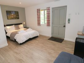 A bedroom with a bed folded towels a window with plaid curtains a door and wooden flooring at Sycamore in Cowbridge