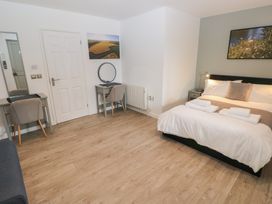 A bedroom with a double bed with towels on it two desks with chairs and framed pictures on the walls at Sycamore in Cowbridge
