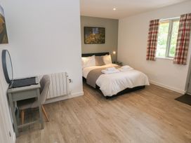 A bedroom with a double bed bedside table a desk chair window and curtains at Sycamore in Cowbridge