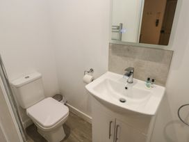 A bathroom with a toilet sink mirror and toiletries at Sycamore in Cowbridge