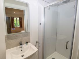 A bathroom with a white sink and a mirror above it next to a glass shower enclosure at Sycamore in Cowbridge