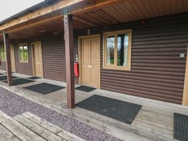 Exterior of a wooden building with brown doors and windows and a covered porch with black mats at Beech in Cowbridge