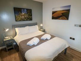 A bedroom with a double bed two bedside tables with lamps and framed pictures on the walls at Beech in Cowbridge