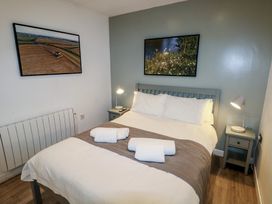 A bedroom with a double bed two bedside tables with lamps and framed pictures on the walls at Beech in Cowbridge
