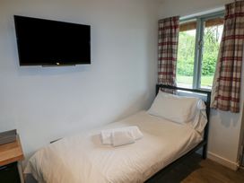 A bedroom with a single bed next to a window and a wall mounted television at Beech in Cowbridge