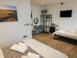 A bedroom with two single beds a desk a chair a small fridge shelves and a wall-mounted TV at Beech in Cowbridge