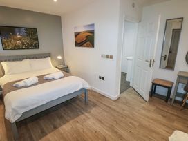 A bedroom with a bed with white linens three towels a bedside table with a lamp an open door a mirror a stool and a desk at Beech in Cowbridge