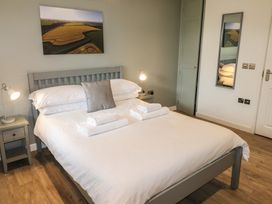 A bedroom with a double bed white bedding towels on bed two bedside tables with lamps wall mirror and landscape picture at Alder in Cowbridge