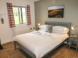 A bedroom with a double bed white bedding bedside tables and lamps a window with check curtains and a landscape picture on the wall at Alder in Cowbridge
