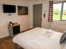 A bedroom with a bed towels a small fridge a television a picture on the wall and a window with curtain at Alder in Cowbridge