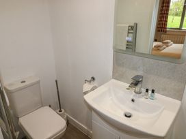 A bathroom with a toilet and sink with toiletries and a mirror reflecting a bedroom at Alder in Cowbridge