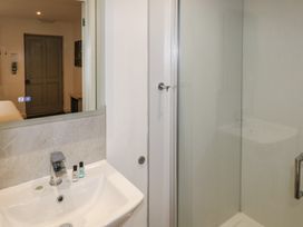 A bathroom sink with toiletries next to a glass shower door at Alder in Cowbridge