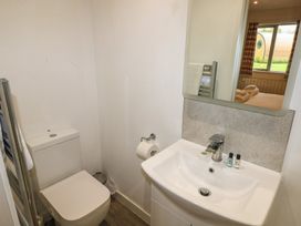 A bathroom with a toilet and a sink with toiletries and a mirror reflecting a bedroom window at Cherry in Cowbridge