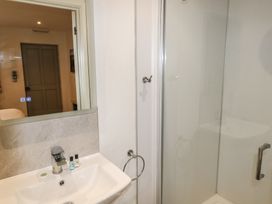 A bathroom with a sink, mirror, shower enclosure, and toiletries at Cherry in Cowbridge
