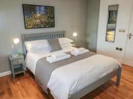 A bedroom with a double bed two bedside tables with lamps a mirror and a painting above the bed at Chestnut in Cowbridge