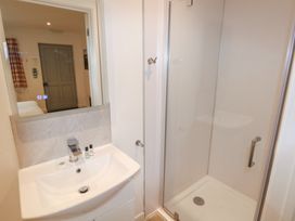 A bathroom with a sink and a mirror next to a shower enclosure with a glass door at Chestnut in Cowbridge