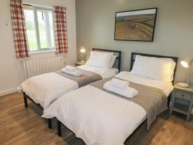 A bedroom with two single beds with white bedding and towels on them bedside tables with lamps and a window with plaid curtains at Oak in Cowbridge