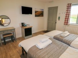 A bedroom with two single beds and towels on them a desk with mirror a television a kettle and a window with plaid curtains at Oak in Cowbridge