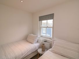 A bedroom with two beds and a window at 61B Fore Street in Kingsbridge