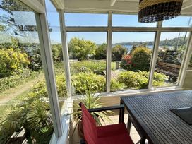 A conservatory with a table and chair overlooking a garden at Nanvivian in Feock near Truro