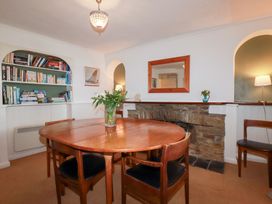 A dining room with a round table and bookshelf at Nanvivian in Feock near Truro