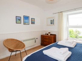 A bedroom with a bed, chair, and artwork on the wall at Nanvivian in Feock near Truro