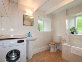 A bathroom with a washing machine, sink, and bathtub at Nanvivian in Feock near Truro